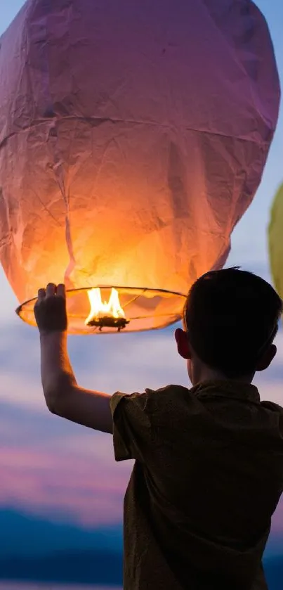 Boy holding a glowing sky lantern during a festival evening.