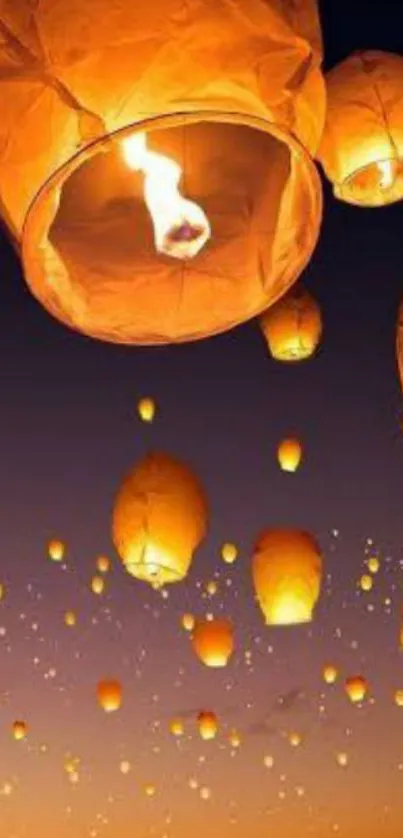 Sky lanterns illuminate the night sky with a warm orange glow.