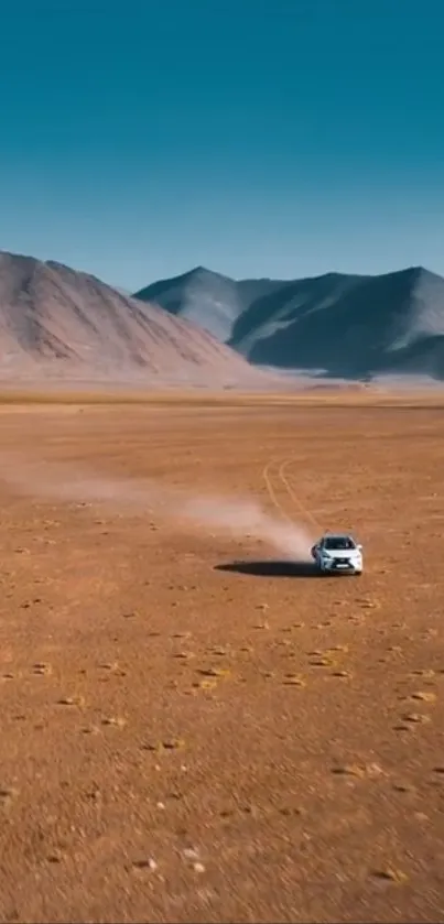 A car travels through a vast desert with mountains under a clear blue sky.