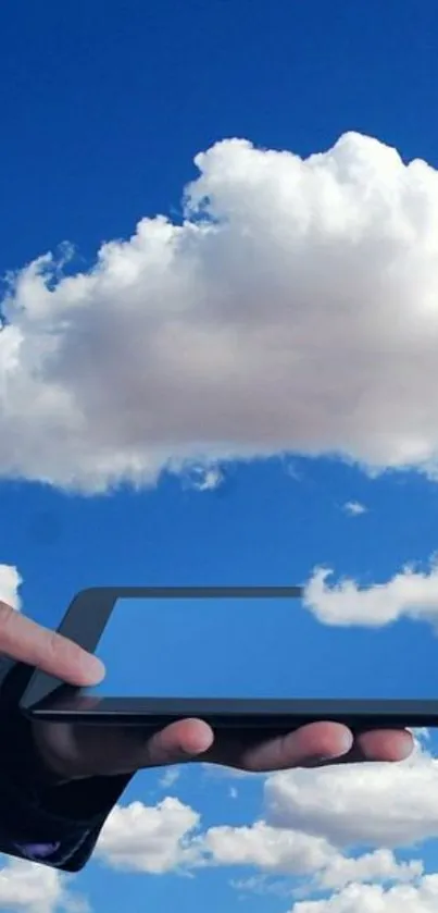 A digital hand touching a tablet with fluffy clouds in a blue sky background.