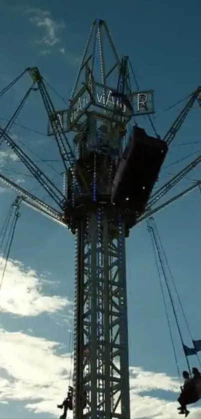 Silhouette of a carnival ride against a blue sky with floating swings.