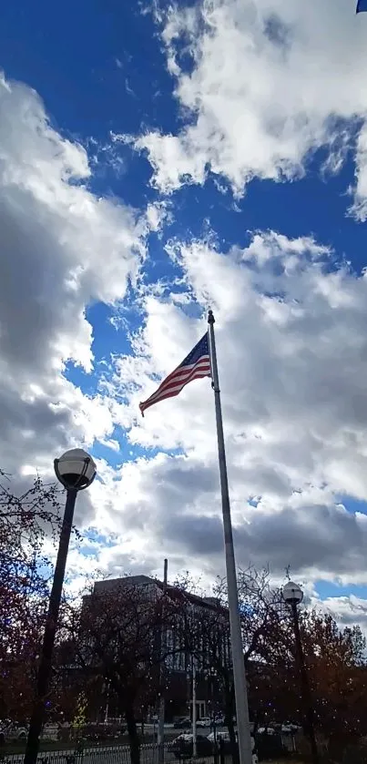 American flag waves under a cloudy blue sky.