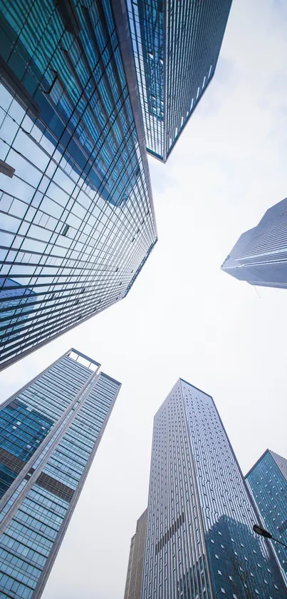 Upward view of skyscrapers against a blue sky with clouds, capturing modern architecture.