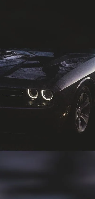 Sleek black car with lit headlights at night.