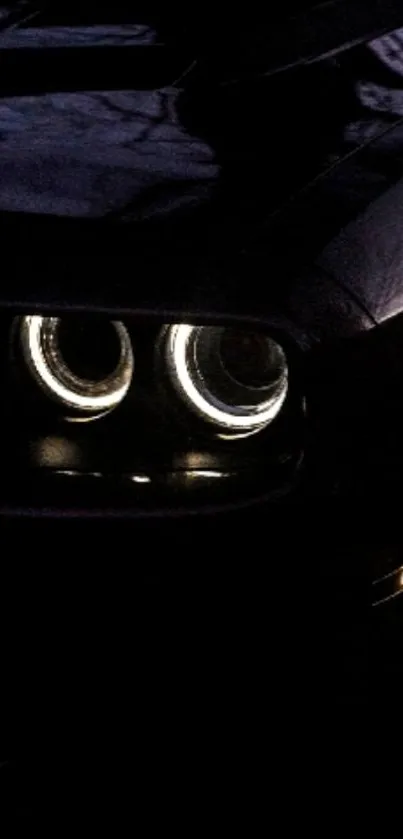 Close-up of black car headlights in dark setting.