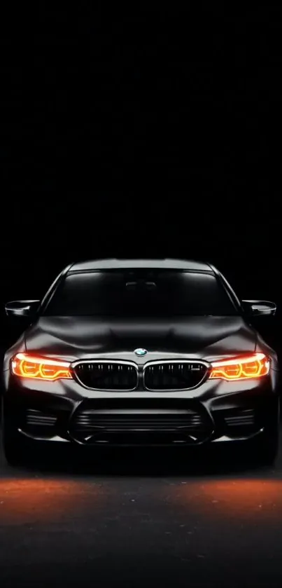 Sleek black car with glowing headlights at night in high-resolution wallpaper.