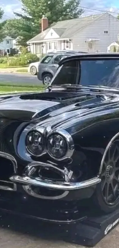 Sleek black classic car parked on a driveway, under a clear sky.