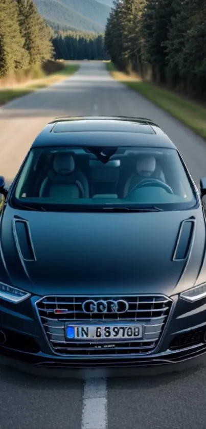 Sleek black car driving on an open road surrounded by nature.