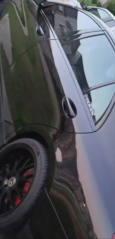 Sleek black car with glossy finish and stylish rims on a driveway.