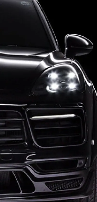 Sleek black car with bright headlights on a dark background.