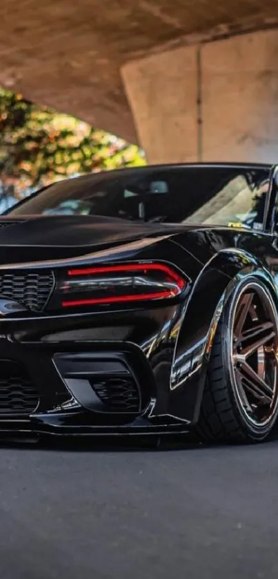 Sleek black sports car under urban bridge.