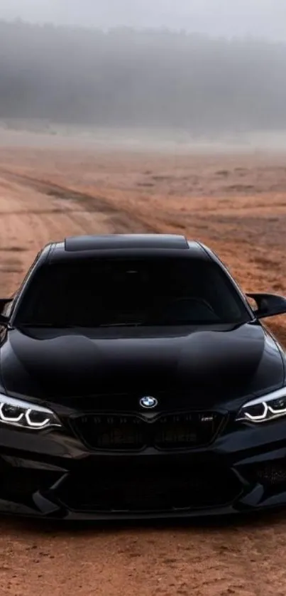 Sleek black car on a dirt road with a foggy background.