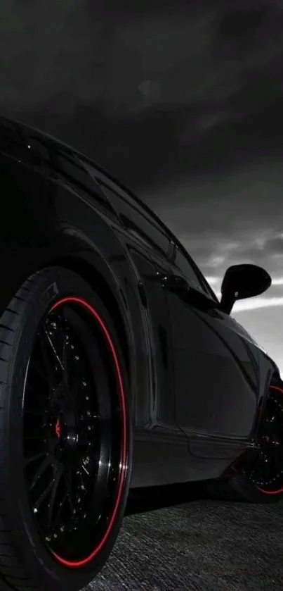 Sleek black car with red accents under a dramatic cloudy sky.