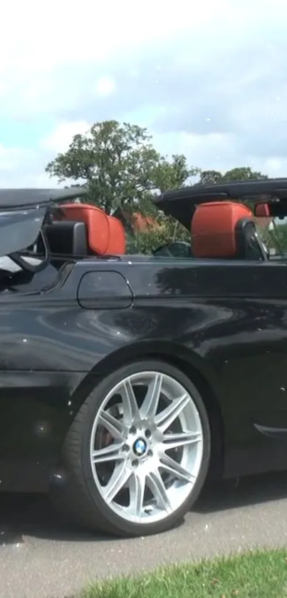 Sleek black convertible car parked outdoors with a stylish design.