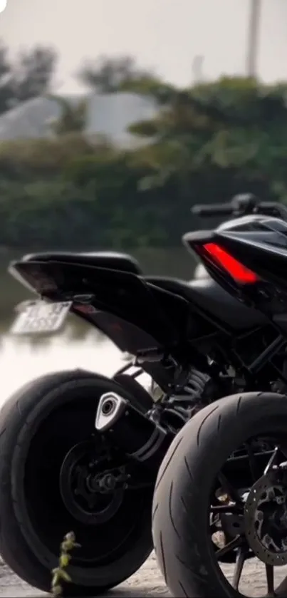 Sleek black motorcycle parked by a scenic outdoor lake.