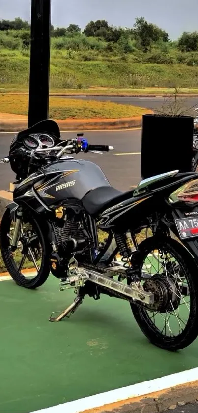 Black motorcycle parked on a road with green scenery background.