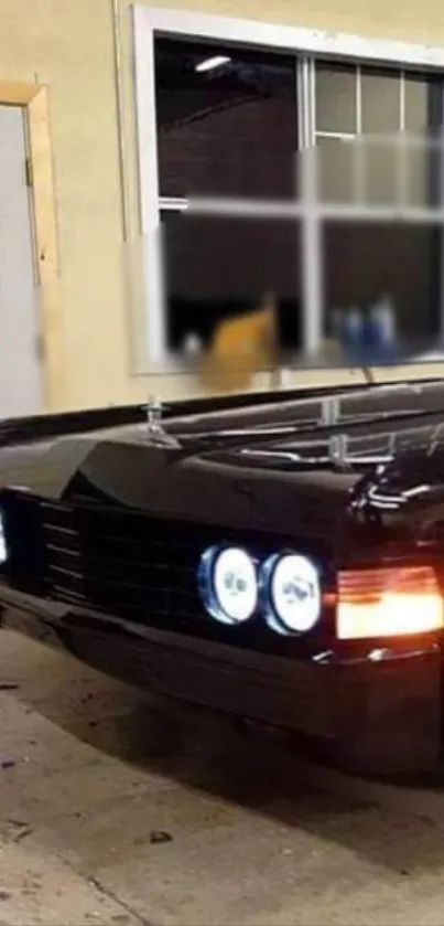 Sleek black muscle car with shining headlights in a garage.