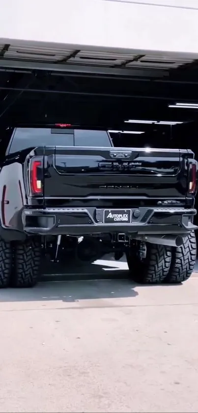 Sleek black pickup truck parked in a garage with rugged tires and modern design.