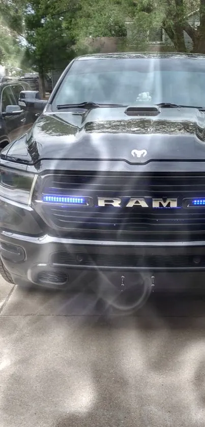 Black RAM truck with blue lights on a sunny driveway.