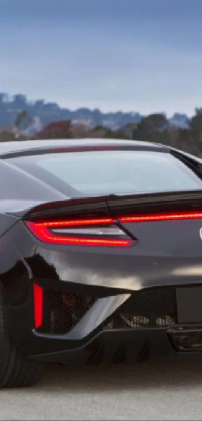 Black sports car on countryside road at sunset.