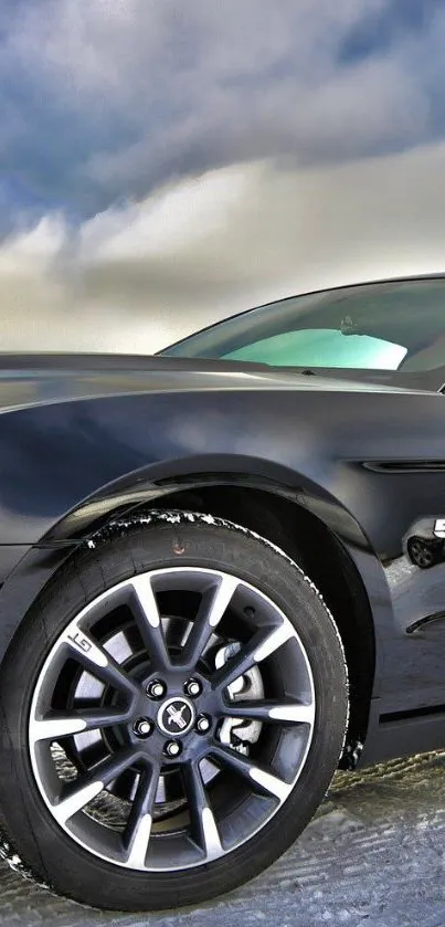 Sleek black sports car with modern wheels on a cloudy day.