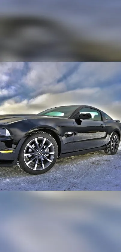 Black sports car on icy ground with a cloudy sky backdrop.