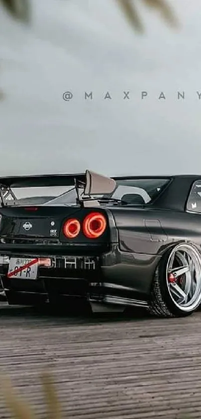 Sleek black sports car with red taillights on a gray background.