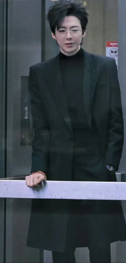 Stylish person in black suit behind glass panel.