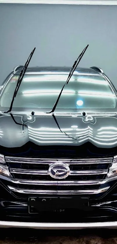 Sleek black SUV car in an indoor wash bay with reflective surfaces.