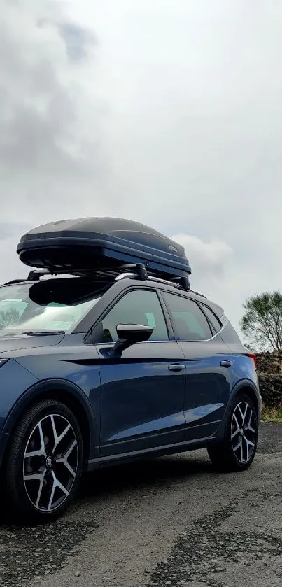 Blue SUV under cloudy sky with rooftop carrier.
