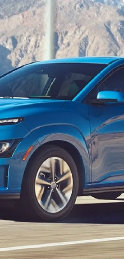 Blue car driving through a scenic desert road with mountains.