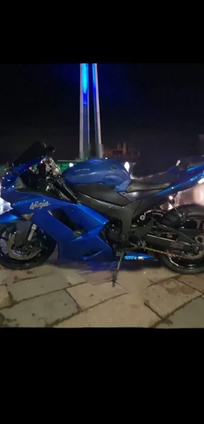 Sleek blue motorcycle parked at night with a glowing backdrop.