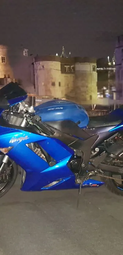 Blue motorcycle in front of historic city at night.