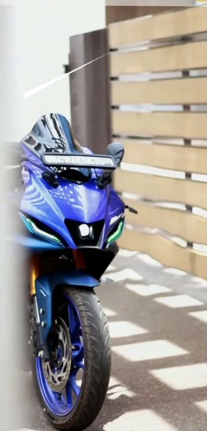 Sleek blue motorcycle parked beside a wooden fence.