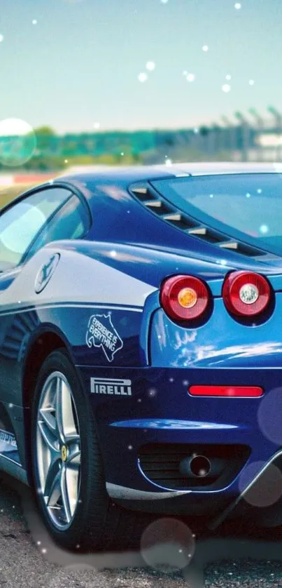 Sleek blue sports car parked on racetrack, shining in the sunlight.