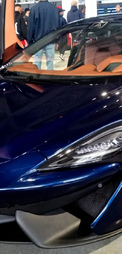 Sleek blue sports car with open doors at an indoor car show.