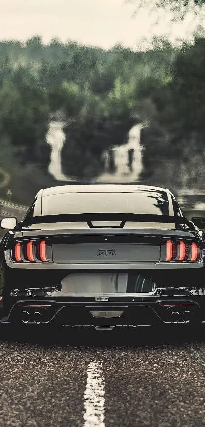 Black car on scenic road with waterfalls and greenery.