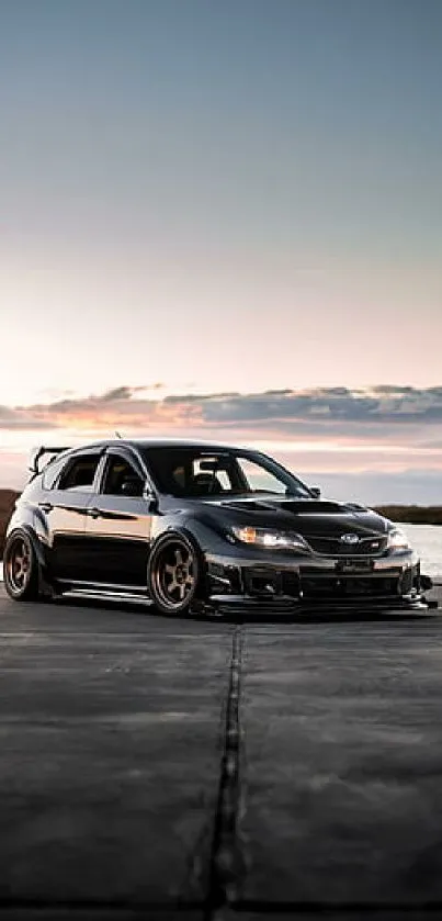 Sleek black car on road with sunset backdrop.