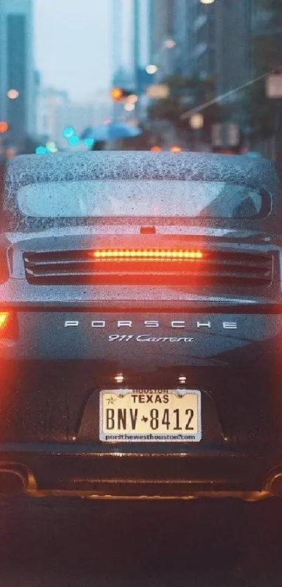 Sleek black sports car on a rainy city street at night.