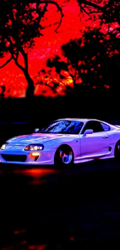 White sports car under red sunset with dark silhouettes of trees.