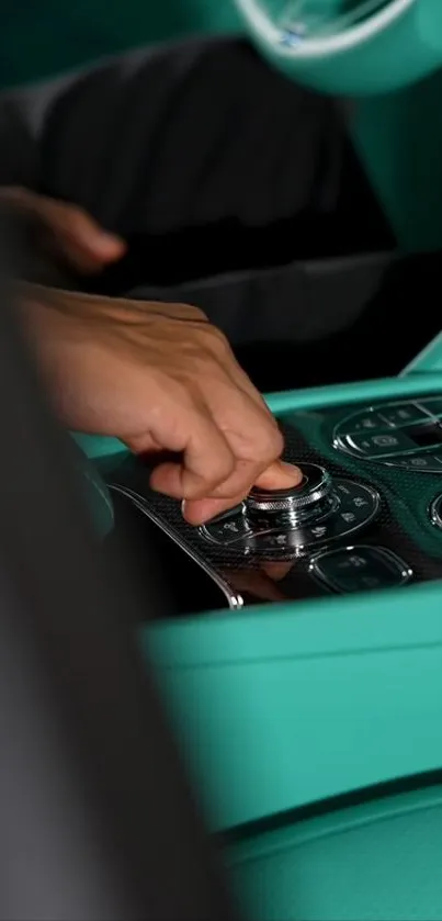 Teal car interior with control panel and hand adjusting knob.