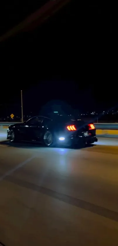 Sleek car driving at night with glowing streetlights.