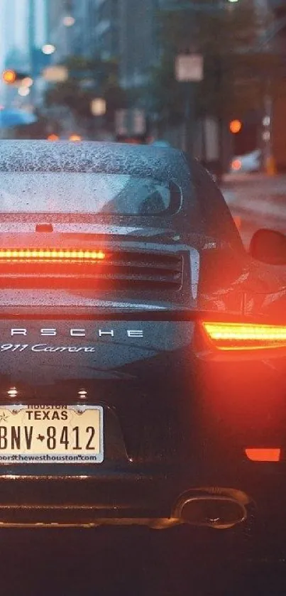 Sleek luxury car with glowing lights on a rainy city street at night.