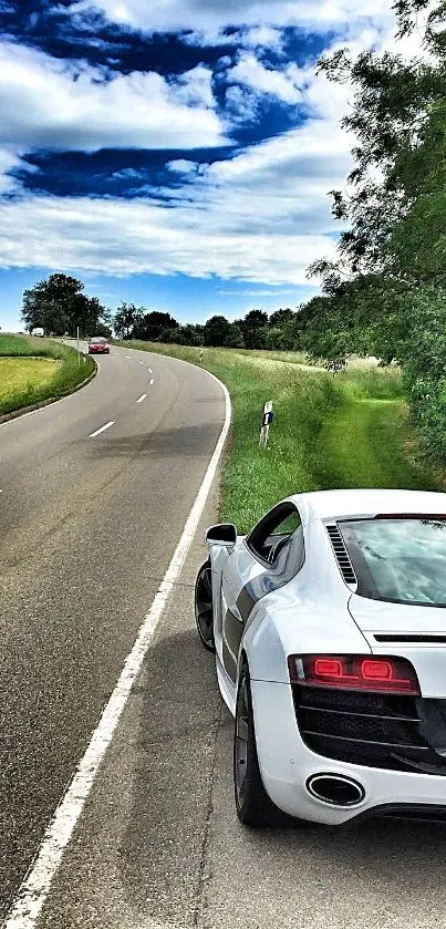 White sports car on a scenic country road under a blue sky with lush greenery.