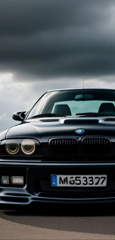 Sleek black car parked under a dramatic, stormy sky on the road.