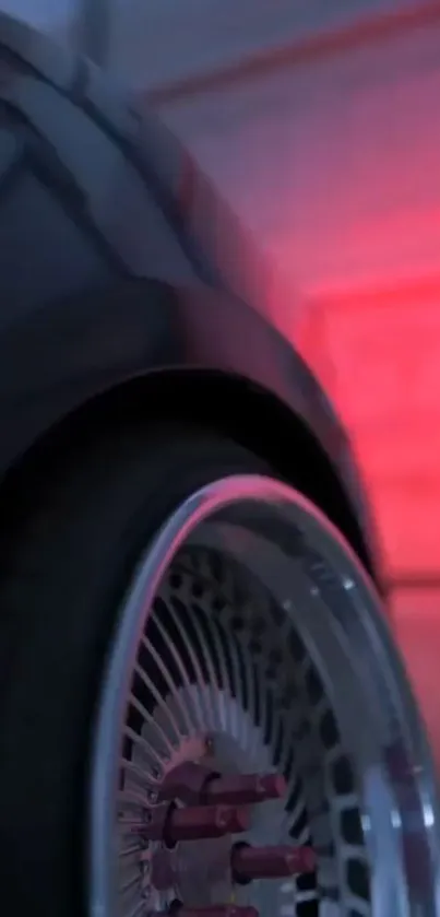 Close-up of car wheel with red lighting in garage.