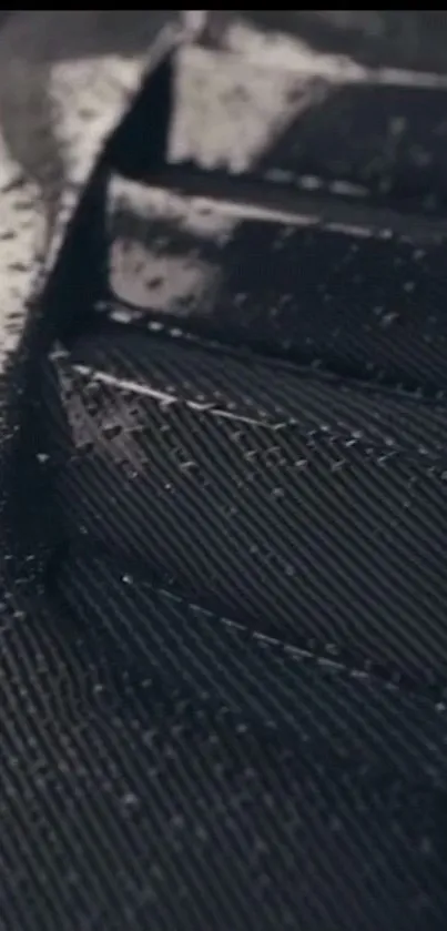 Close-up of dark carbon fiber texture with sleek design.