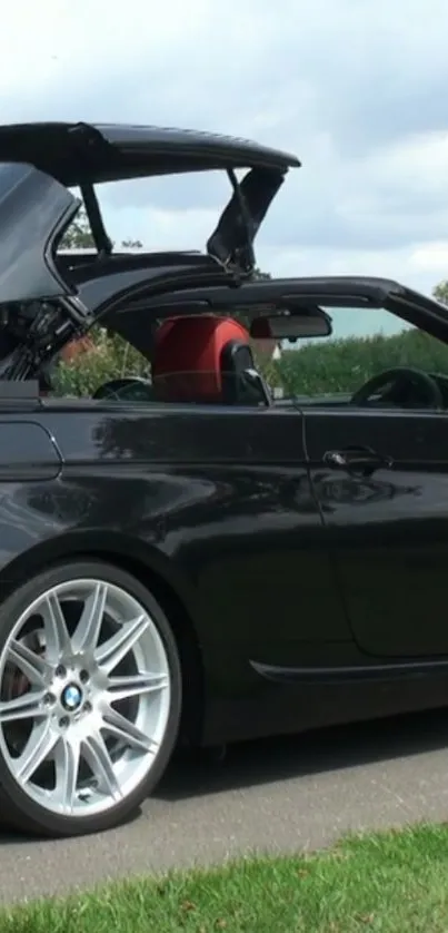 Sleek black convertible car with the roof open on a sunny day.