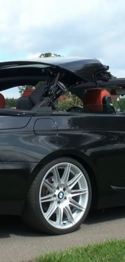 Black convertible car on road close-up with roof down.