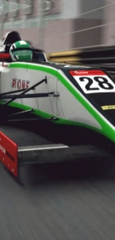 Sleek formula car with green accents speeding on track.